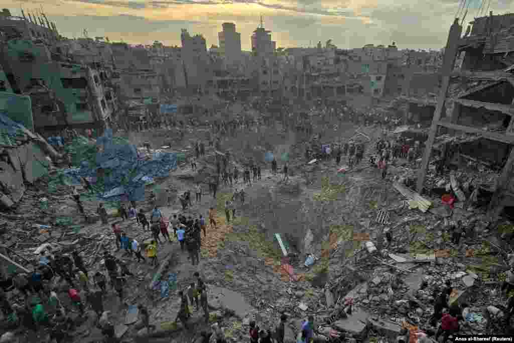 Palestinalylar 2023-nji ýylyň 31-nji oktýabrynda Gazanyň demirgazygyndaky Jabaliýa bosgun düşelgesindäki öýlere Ysraýyl tarapyndan edilen hüjüm ýerinde pidalary gözleýärler.&nbsp;(REUTERS / Anas al-Shareef)