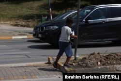 Maloletni dečak moli za novac u zamenu za čišćenje prozora na automobilima u Prištini na Kosovu.