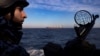 A member of Ukraine's coast guard mans a gun on a patrol boat as a cargo ship passes by in the Black Sea in February 2024. 