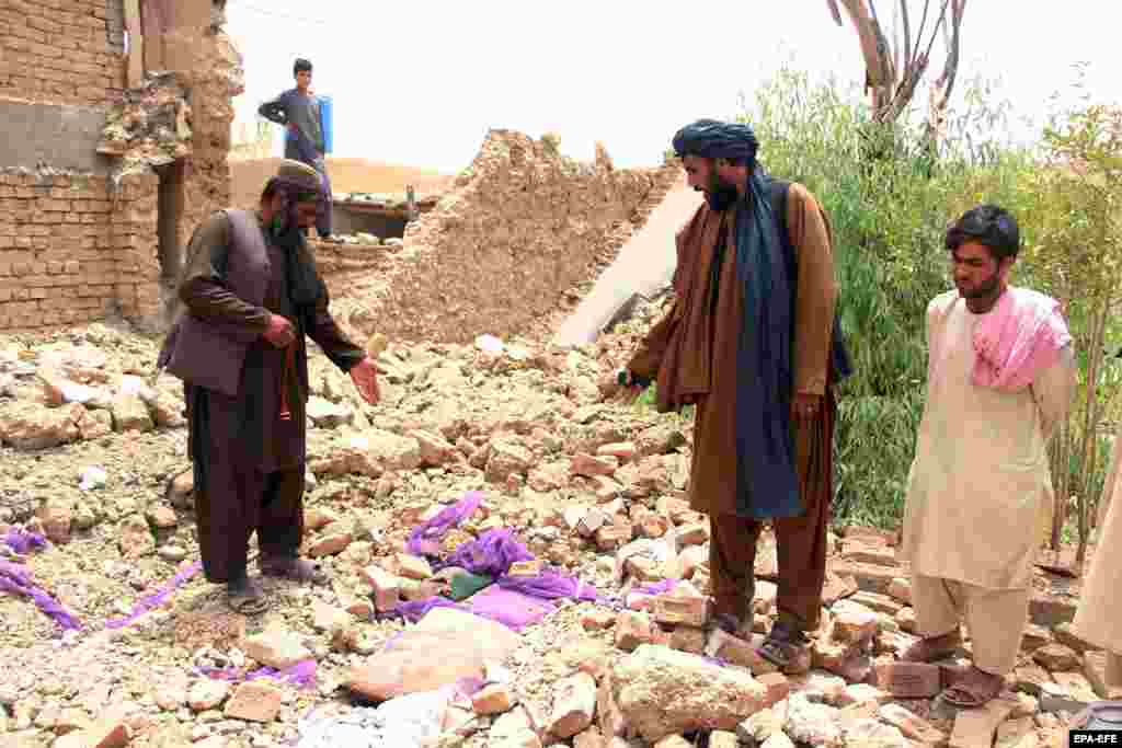 People stand in the rubble of a collapsed building in Kandahar on July 22. 