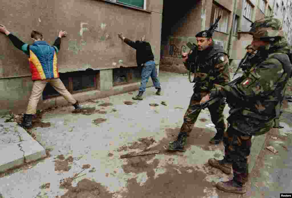Italian soldiers guard suspected arsonists in Sarajevo in March 1996. Tens of thousands of NATO troops were deployed to the conflict in Bosnia. Since then the alliance invoked Article 5 against Afghanistan after the September 11, 2001 terrorist attacks, and intervened in Libya's civil war.