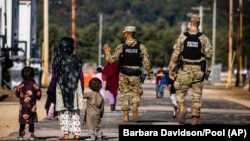 Military police walk past Afghan refugees at the Ft. McCoy U.S. Army base in Wisconsin in September.