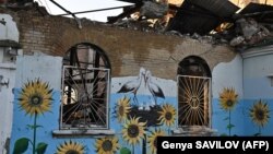 Изображения подсолнухов и аистов на стене сильно поврежденного дома культуры в Ирпене, городе под Киевом 