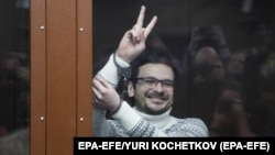 Ilya Yashin gestures from inside a defendant's cage in a Moscow courtroom in December 2022.