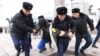 Полицейские задерживают и ведут к автозаку активиста на площади Республики в Алматы. 20 ноября 2022 года