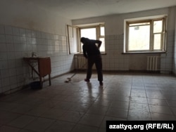 A woman washes the floor in a room called a kitchen. It contains one sink for the entire floor.
