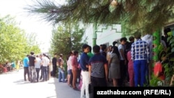 Türkmenistanyň döwlet ulaglar we aragatnaşyk institutynyň köne binasynyň okuw korpuslarynyň biriniň öňünde sanawa durmak üçin garaşyp duran ýaşlar
