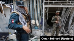 Afghan security personnel inspect the site of a suicide attack outside a bank near the U.S. Embassy in Kabul on August 29.