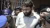 In this file photo from March 29, 2002, Pakistani police surround a handcuffed Omar Sheikh as he comes out of a court in Pakistan's port city of Karachi.