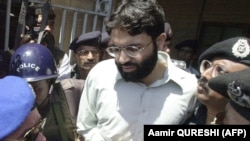 In this file photo from March 29, 2002, Pakistani police surround a handcuffed Omar Sheikh as he comes out of a court in Pakistan's port city of Karachi.
