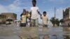 People wade through flood water as they make their way on an inundated street after heavy downpour in Karachi on August 31. 