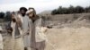 Afghan men show shrapnel from missiles that struck their village in the U.S.-led air strike in Farah Province.