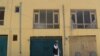 FILE: An Afghan man talks on a phone in front a guest house used by foreign workers and that was attacked by gunmen in Kabul in May.