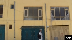 FILE: An Afghan man talks on a phone in front a guest house used by foreign workers and that was attacked by gunmen in Kabul in May.