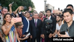 На фото с сайта президента Шавкат Мирзиёев (в центре) позирует с блогерами и журналистами в Самарканде в августе 2019 года.