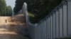 A Polish border guard patrols the area of a newly built metal wall on the border between Poland and Belarus, near Kuznica, Poland.