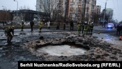 Rescue workers and investigators attend the scene of a Russian strike on Kyiv on January 18. 