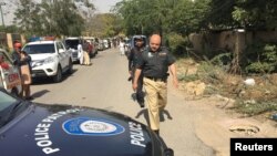 FILE: A policeman walks past a police vehicle in Karachi.