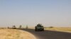Afghan security personnel sit on armored vehicles amid an ongoing battle with Taliban militants in the Gereshk district of Helmand Province on July 22.