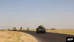 Afghan security personnel sit on armored vehicles amid an ongoing battle with Taliban militants in the Gereshk district of Helmand Province on July 22.