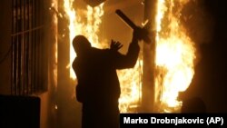 A rioter throws a street sign into the burning U.S. Embassy in Belgrade, Serbia, in February 2008.