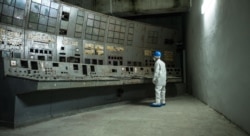 Adam Çernobyl AES-niň üsti örtülen reaktorynyň dolandyryş bölümine seredýär.