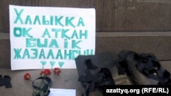 Плакат с требованием и цветы у монумента Независимости в Алматы. 6 января 2012 года. 