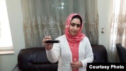 Radio Azadi journalist Nazeefa Mahboobi displays the award she received from local NGOs for her investigative reporting.
