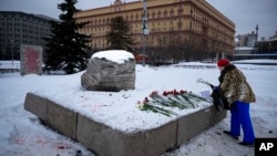 With Russia's Federal Security Service building in the background, a woman lays flowers to pay tribute to Aleksei Navalny at a monument in Moscow dedicated to gulag prisoners.
