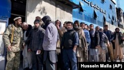 A Taliban fighter stands guard as people wait to enter a bank in Kabul on February 13.