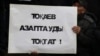 Қаңтар қырғыны құрбандарын еске алу акциясында президент Қасым-Жомарт Тоқаевтан Қазақстан түрмелеріндегі азаптауды тоқтату талап еткен жазуы бар плакат ұстап тұрған адам. Алматы, 13 ақпан 2022 жыл.
